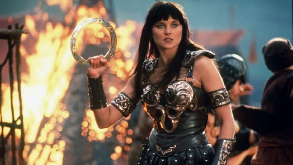 Lucy Lawless organiza fundo para ajudar dublê de Xena Lucy Lawless em Xena: A Princesa Guerreira (Reprodução)