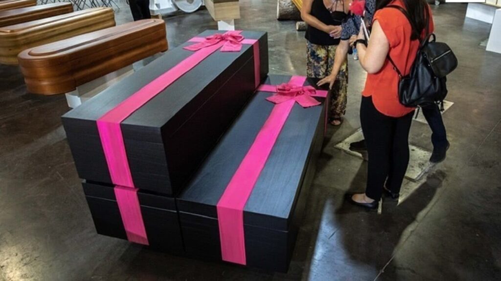 Empresa faz caixões inspirados em Round 6 Caixões novos da empresa Arcae são pretos e possuem um laço rosa sobre a tampa (Reprodução/Twitter)