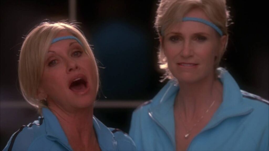 Olivia Newton-John teve crise de riso nos bastidores de Glee: “maxilar dolorido” Olivia Newton John e Jane Lynch em Glee Reproducao