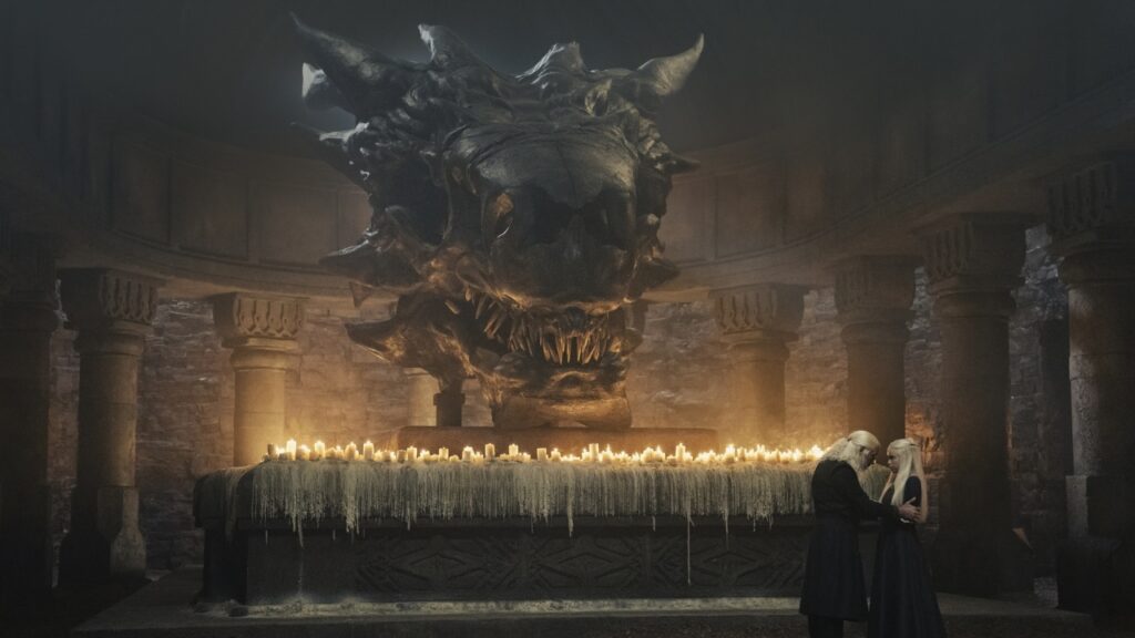 Rei Viserys I Targaryen (Paddy Considine) e Princesa Rhaenyra (Milly Alcock) em frente ao crânio de Balerion em A Casa do Dragão (Reprodução / HBO)