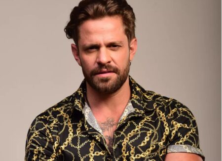 Imagem do ator Alejandro Claveaux com uma expressão sexy caracterizado como o cantor sertanejo Deivid Cafajeste da série Resnga Hits