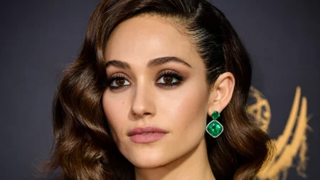 Por que Emmy Rossum saiu de Shameless? A verdade completa Mulher em close com brinco verde em evento para pauta sobre Emmy Rossum.