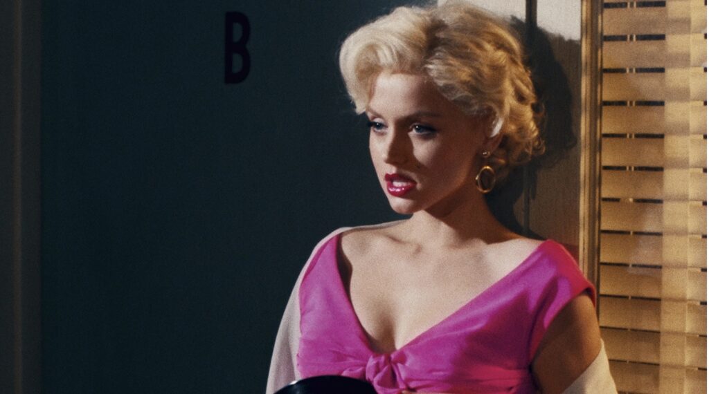 Ana de Armas em cena de Blonde sensualizando em um vestido rosa decotado