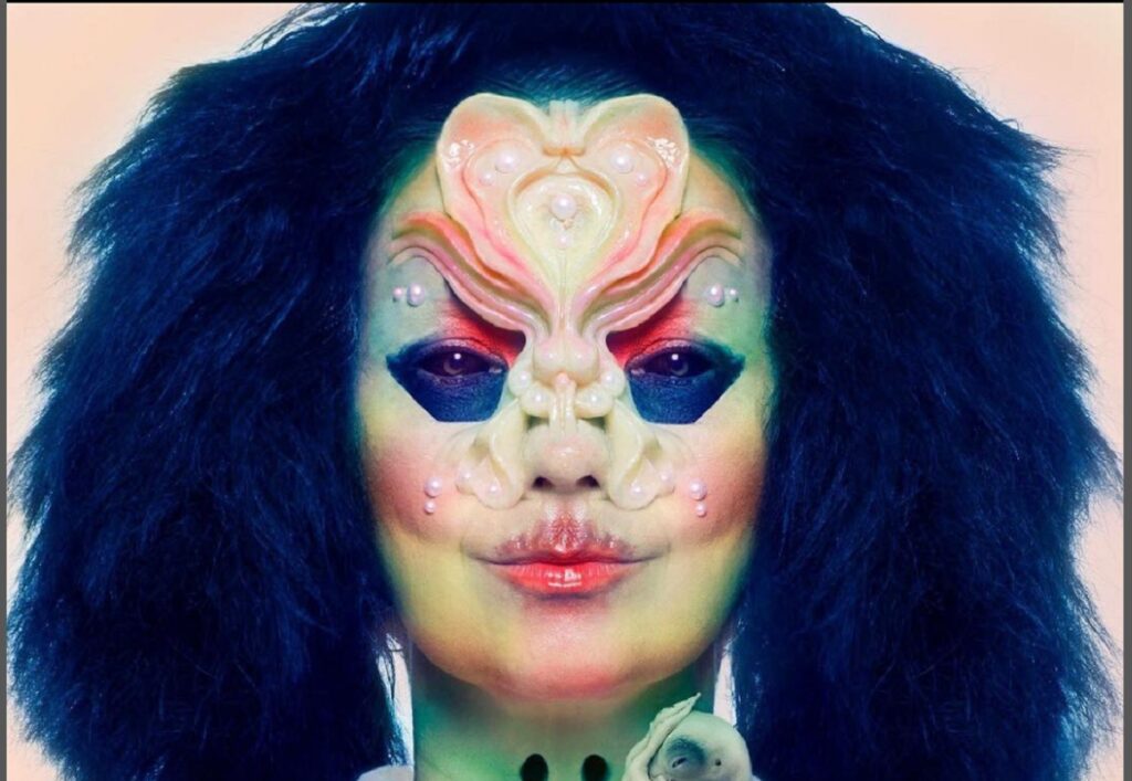 Close de Björk com uma máscara e maquiagem em um estilo alienigena