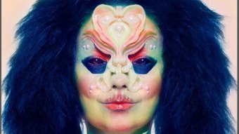Close de Björk com uma máscara e maquiagem em um estilo alienigena