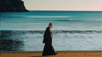 Cartaz de O santo de todos - A vida e missão de Santo Antônio Maria Claret mostra arcebispo caminhando na beira da praia