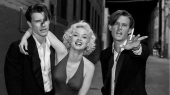 Xavier Samuel como Charles Chaplin Jr., Ana de Armas como Marilyn Monroe e Evan Williams como Edward G. Robinson Jr. abraçados em cena de Blonde