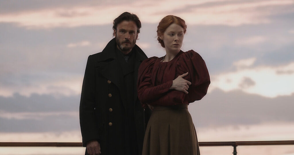 Qual a relação de Eyk e Daniel com Maura em 1899? Andreas Pietschmann como Eyk Larsen e Emily Beecham como Maura Franklin em 1899