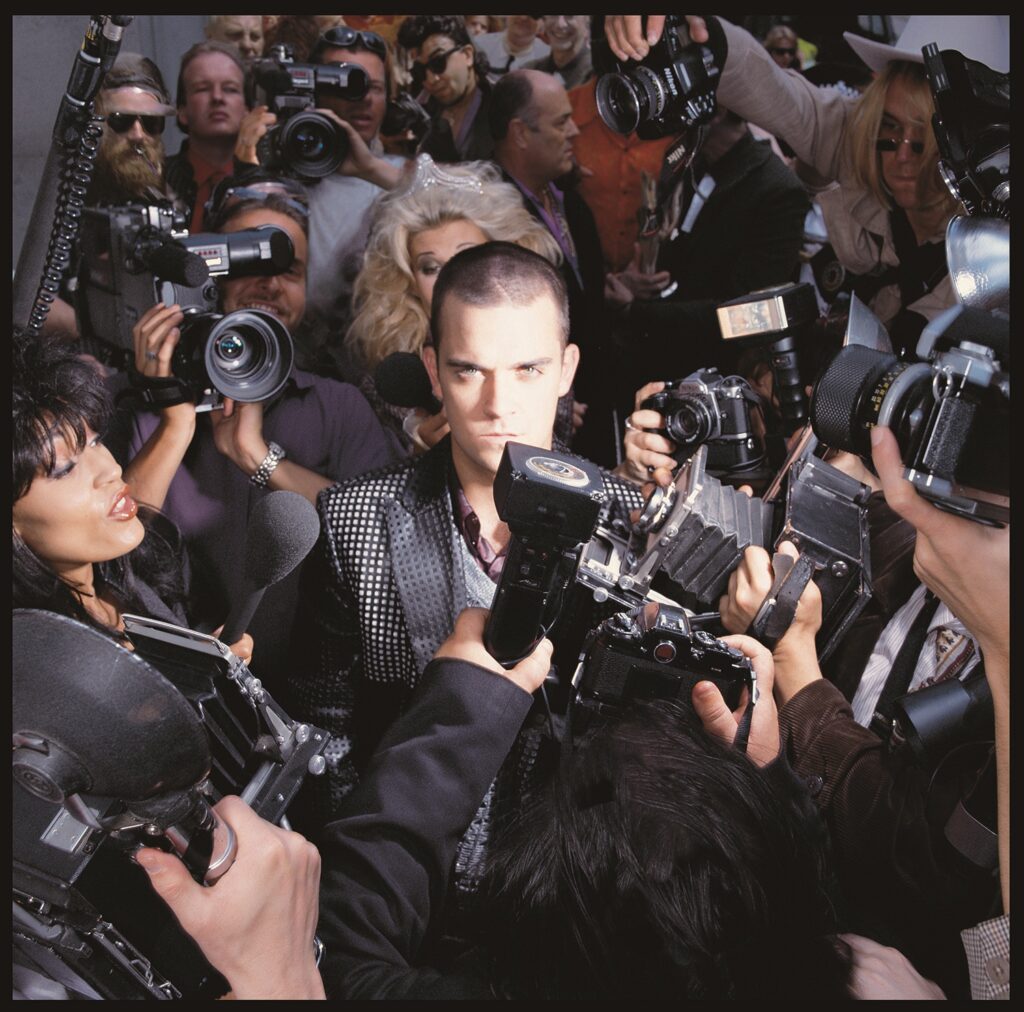 Pôster de Better Man recria de forma inusitada capa de álbum de Robbie Williams 2 Capa do álbum "Life Thru A Lens" (1997)