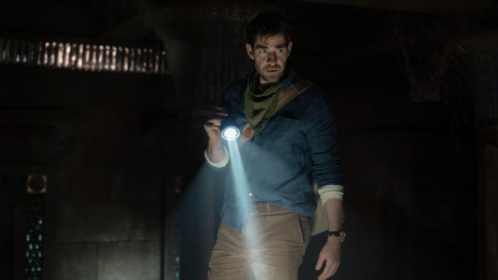Como A Fonte da Juventude é diferente de outros filmes de caça ao tesouro John Krasinski como Luke em A Fonte da Juventude (Reprodução / Apple TV+)
