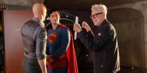 Filmes da DC: ordem do DCEU e do novo DCU explicada Nos bastidores da filmagem de Superman (2025), um dos novos filmes da DC, Nicholas Hoult aparece caracterizado como Lex Luthor, de costas, enquanto David Corenswet, no traje completo de Superman, conversa com o diretor James Gunn, que sorri de óculos e barba grisalha enquanto segura páginas do roteiro.