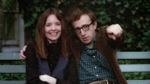 Diane Keaton e Woody Allen sentados em um banco de parque na clássica cena do filme Annie Hall, de 1977, com a personagem Annie sorrindo e Alvy apontando para a frente.