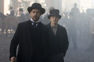 O Assassinato de Jesse James pelo Covarde Robert Ford (2007) IMDb.jpg Alt text: Brad Pitt como Jesse James e Casey Affleck como Robert Ford em cena do filme O Assassinato de Jesse James pelo Covarde Robert Ford (2007), caminhando por uma rua empoeirada do Velho Oeste com figurinos de época; exemplo de filmes de faroeste com trilha sonora marcante composta por Nick Cave e Warren Ellis.