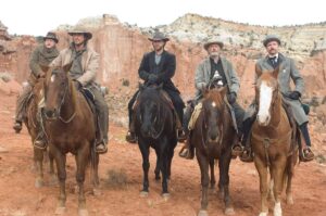 Christian Bale como Dan Evans e Russell Crowe como Ben Wade, acompanhados de outros homens a cavalo diante de formações rochosas no filme Os Indomáveis (2007).