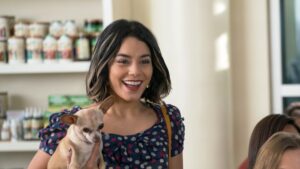 Sessão da Tarde de hoje exibe Nossa Vida com Cães, com Vanessa Hudgens Vanessa Hudgens como Tara em Nossa Vida com Cães, segurando um pequeno cachorro marrom-claro nos braços enquanto sorri em um ambiente ensolarado; a cena destaca a relação afetuosa entre a personagem e o animal, elemento central da trama sobre conexões humanas e seus cães de estimação.