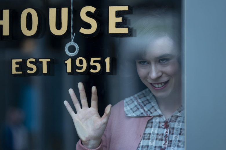 IT: Bem-vindos a Derry e mais estreias da semana nos streamings e cinemas Personagem de IT: Bem-vindos a Derry sorri de forma enigmática atrás de uma vitrine com letreiro antigo