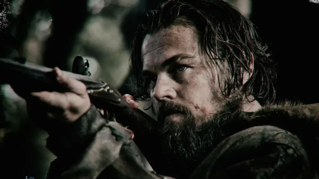 Cena do filme O Regresso: um homem barbudo mira um rifle com expressão determinada em meio a uma floresta escura, destacando o clima de tensão da cena.