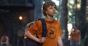 Disney+ libera recap da 1ª temporada de Percy Jackson; confira Percy Jackson observa a floresta no Acampamento Meio-Sangue usando a camiseta laranja dos semideuses.