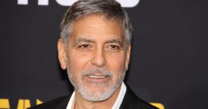 George Clooney posa em evento, usando terno escuro e barba grisalha