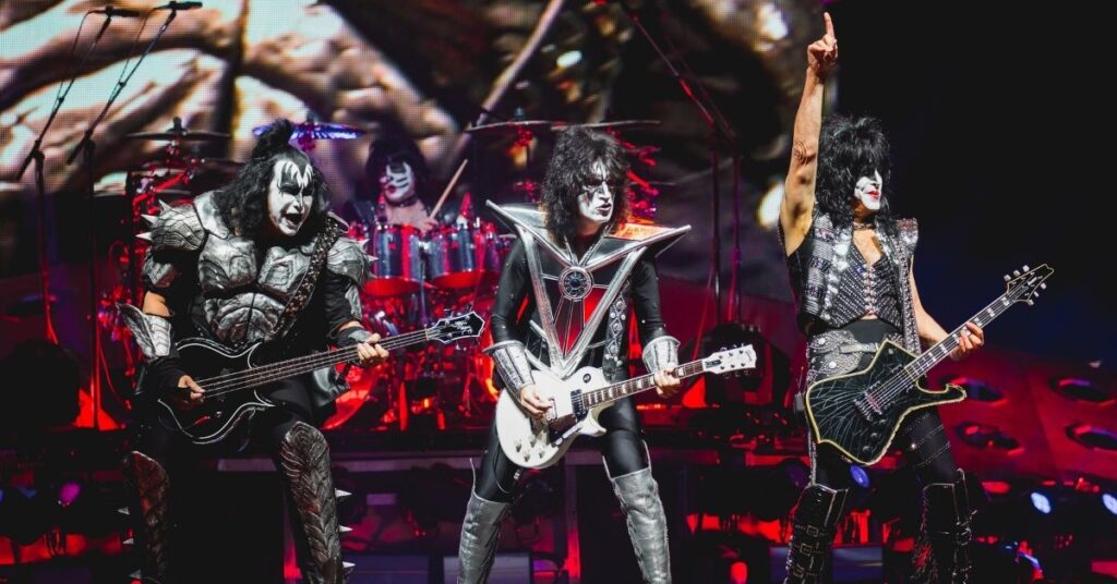 KISS terá cinebiografia e diretor antecipa tom explosivo da produção Membros do KISS se apresentam no palco com figurinos clássicos e maquiagem marcante durante show de rock.
