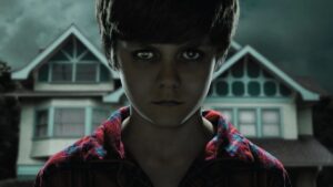 Garoto com olhar assustador em frente a uma casa sombria, imagem promocional da franquia Insidious para quem busca assistir sobrenatural online.
