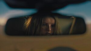 Cena tensa do filme Hereditário mostra personagem refletida no retrovisor do carro, transmitindo clima de suspense e terror psicológico