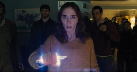 Emily Blunt segura objeto luminoso em cena tensa do filme Disclosure Day, enquanto outras pessoas observam ao fundo