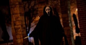 Ghostface aparece encapuzado segurando faca em cena noturna do filme Pânico 7