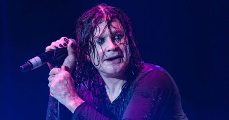 Ozzy Osbourne ganha cinebiografia e família já escolhe ator; veja o que se sabe Ozzy Osbourne se apresenta ao vivo no palco, segurando o microfone durante show, com cabelos molhados e iluminação roxa ao fundo