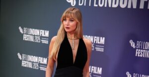 Jennifer Lawrence posa no tapete vermelho do BFI London Film Festival 2025, usando vestido longo preto decotado, com colar dourado, durante o evento em Londres