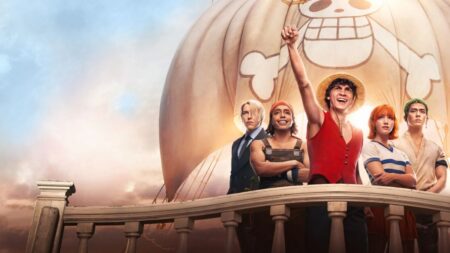 Elenco principal de One Piece live-action reunido no navio Going Merry, com Luffy em destaque erguendo o braço, ao lado de Zoro, Nami, Usopp e Sanji, diante da vela com o símbolo dos Chapéus de Palha