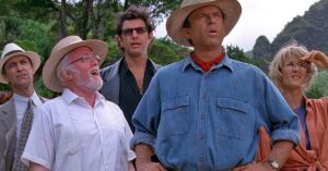 Ator relembra furacão que destruiu o set de Jurassic Park: ‘estivemos perto da morte’ Cena de Jurassic Park - Parque dos Dinossauros mostra personagens observando algo à distância em meio à paisagem tropical do parque.