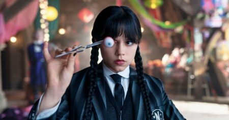 Jenna Ortega caracterizada como Wandinha segura um globo ocular em cena da série da Netflix