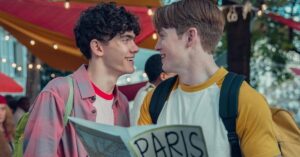 Nick e Charlie conversam sorrindo enquanto seguram um mapa em cena da série Heartstopper da Netflix