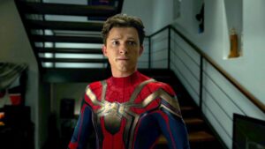 Tom Holland surpreende ao detonar filmes da própria carreira: ‘Era uma porcaria’ Tom Holland aparece usando o traje do Homem-Aranha dentro de uma casa, com expressão preocupada, diante de uma escada moderna ao fundo.