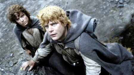 Novo capítulo de O Senhor dos Anéis é anunciado; saiba mais Frodo Bolseiro e Samwise Gamgee aparecem escalando uma encosta rochosa em cena do filme O Senhor dos Anéis: O Retorno do Rei, usando capas de viagem enquanto observam algo acima.