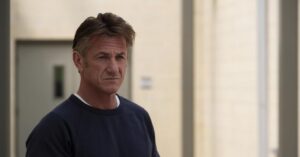 Sean Penn com expressão séria, usando moletom escuro em ambiente externo