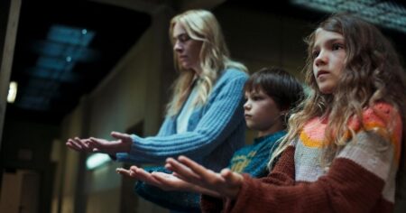 Série Depois da Cabana: saiba onde assistir, elenco e episódios Mulher e duas crianças com expressão séria em ambiente fechado na série Depois da Cabana