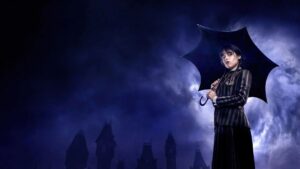 Wandinha 2° temporada: sinopse, novos atores e onde assistir Wednesday Addams aparece vestida com uniforme escuro e segurando um guarda-chuva preto enquanto observa o horizonte sob chuva, tendo ao fundo a silhueta gótica da Academia Nevermore na série Wednesday.