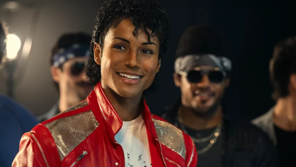 Michael Jackson: bastidores do filme biográfico é revelado em vídeo; confira Jaafar Jackson caracterizado como Michael Jackson com jaqueta vermelha icônica sorri durante gravação, com dançarinos ao fundo