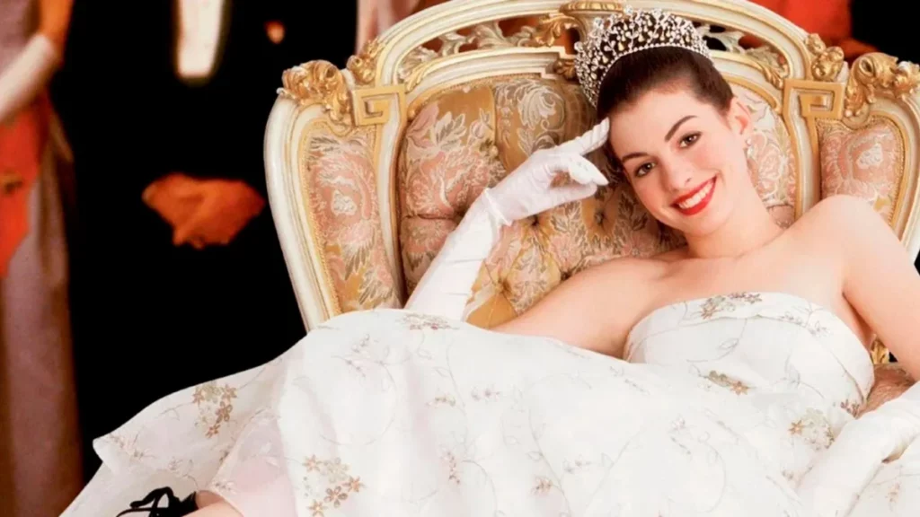O Diário da Princesa 3: Anne Hathaway revela o futuro da produção; confira a declaração Anne Hathaway como princesa Mia em cena de O Diário da Princesa, usando vestido elegante e tiara, sentada em um trono sofisticado, imagem ilustrativa relacionada a O Diário da Princesa 3.