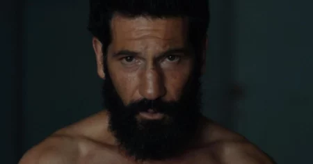 Jon Bernthal como Justiceiro em close com olhar intenso e expressão séria em cena escura