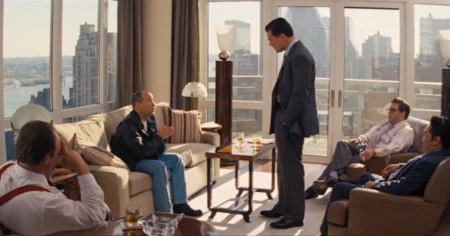 cena do filme O Lobo de Wall Street mostra Leonardo DiCaprio em sala de cobertura com vista para Manhattan e outros personagens ao redor