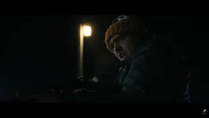 Personagem em cena noturna iluminada por poste segura arma em ambiente escuro no filme Resident Evil
