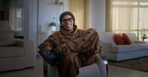 Ronaldinho Gaúcho sentado em poltrona durante entrevista para documentário da Netflix, em ambiente interno iluminado