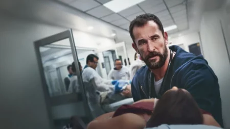 Arte promocional de The Pitt mostrando um médico em um atendimento tenso.