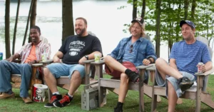 Chris Rock, Kevin James, David Spade e Adam Sandler sentados à beira de um lago em cena de Gente Grande
