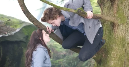 Crepúsculo assistir online: onde ver a saga completa, ordem e qualidade Cena romântica de Bella e Edward em Crepúsculo assistir online, com Edward em uma árvore olhando para Bella