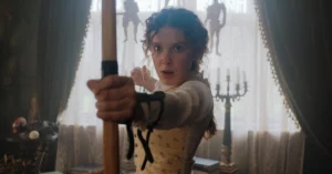 Millie Bobby Brown aparece como Enola Holmes segurando arco e flecha em cena de ação da franquia da Netflix