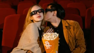 Pessoas com pipoca em sala de cinema em pauta sobre melhores filmes de comédia romântica